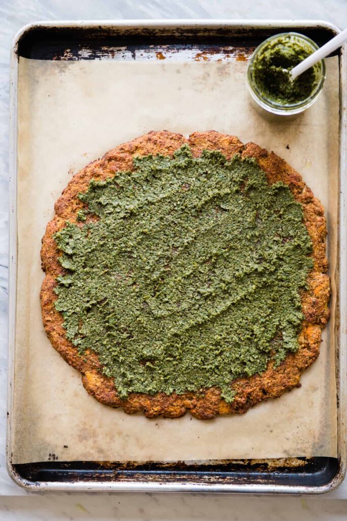 Arugula-topped pesto pizza made with grain-free sweet potato crust