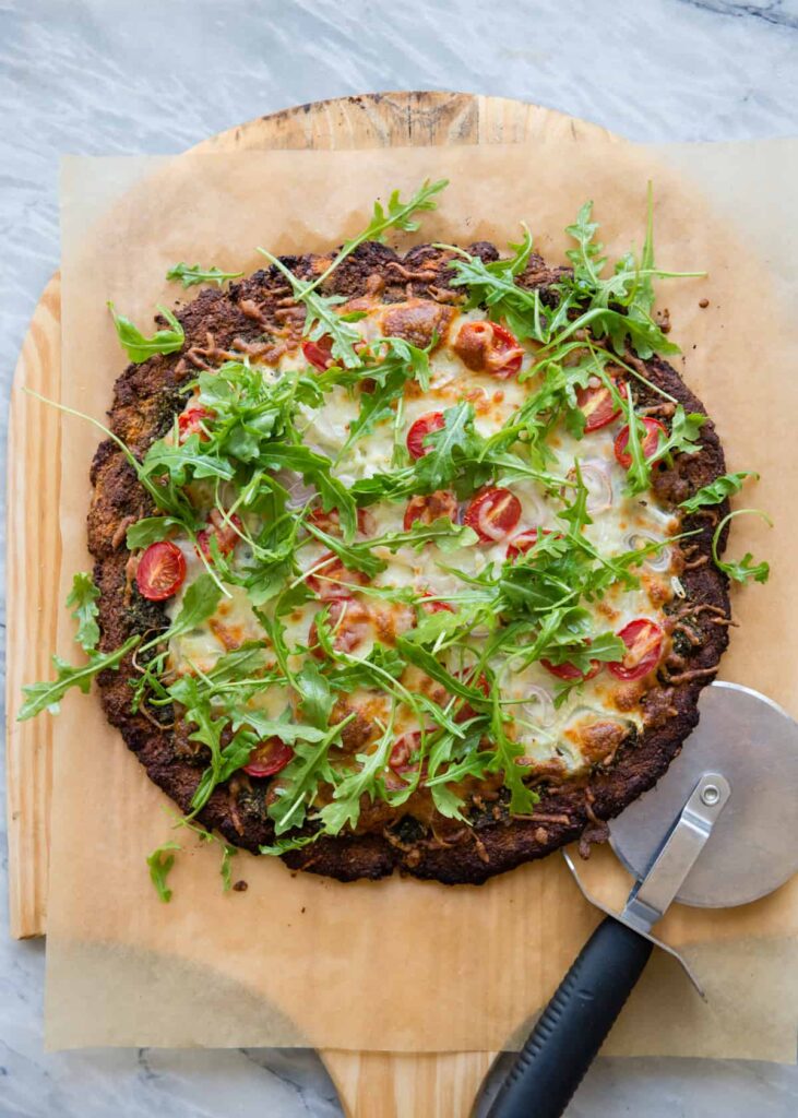 Arugula-topped pesto pizza made with grain-free sweet potato crust