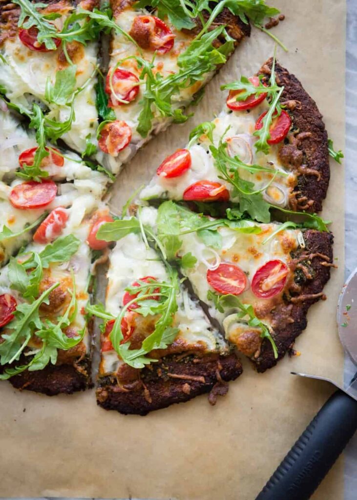 Arugula-topped pesto pizza made with grain-free sweet potato crust